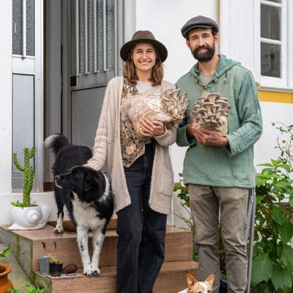 Couple with dog showing freshly harvested oyster mushrooms, the results of mushroom growing kits and home cultivation kits.