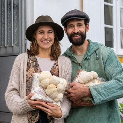 Smiling growers holding large lion's mane mushroom growing kit fruiting blocks showing successful indoor cultivation at home.