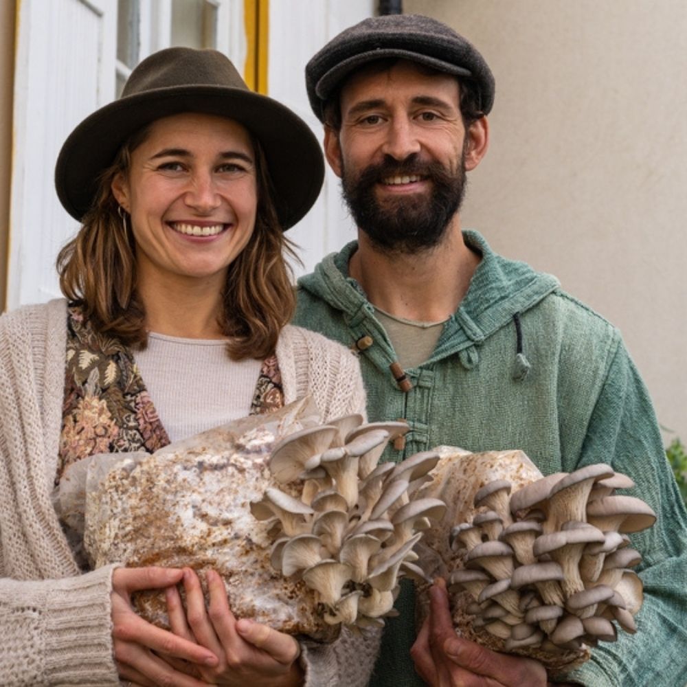 Smiling couple holding large oyster mushroom grow kit blocks, representing home mushroom growing and small-scale cultivation.
